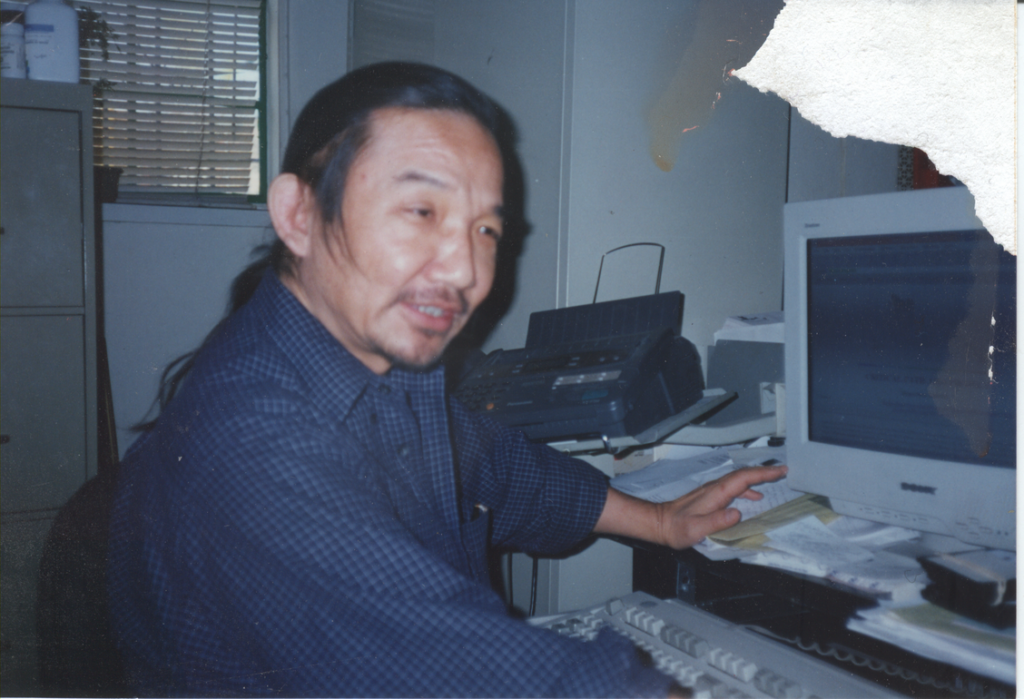 Kiyoshi Kuromiya sitting at desk